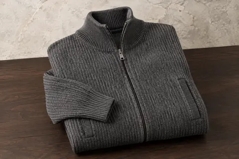 Cardigan homme en maille côtelée à col montant, fermeture zippée et deux poches, présenté à plat.
