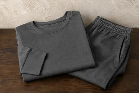Ensemble de pyjama homme en coton à manches longues, plié sur une surface en bois foncé