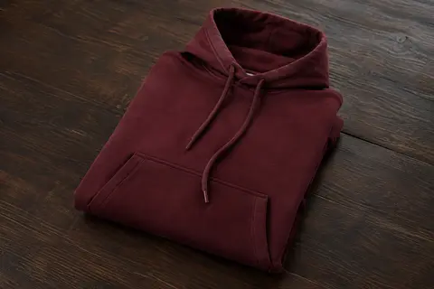 Sweat Carhartt à capuche et coupe ample, plié sur une surface en bois foncé, avec ses poches avant visibles.