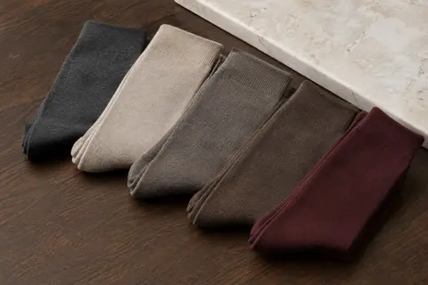 Lot de chaussettes unies pour homme soigneusement pliées sur une surface en bois foncé.
