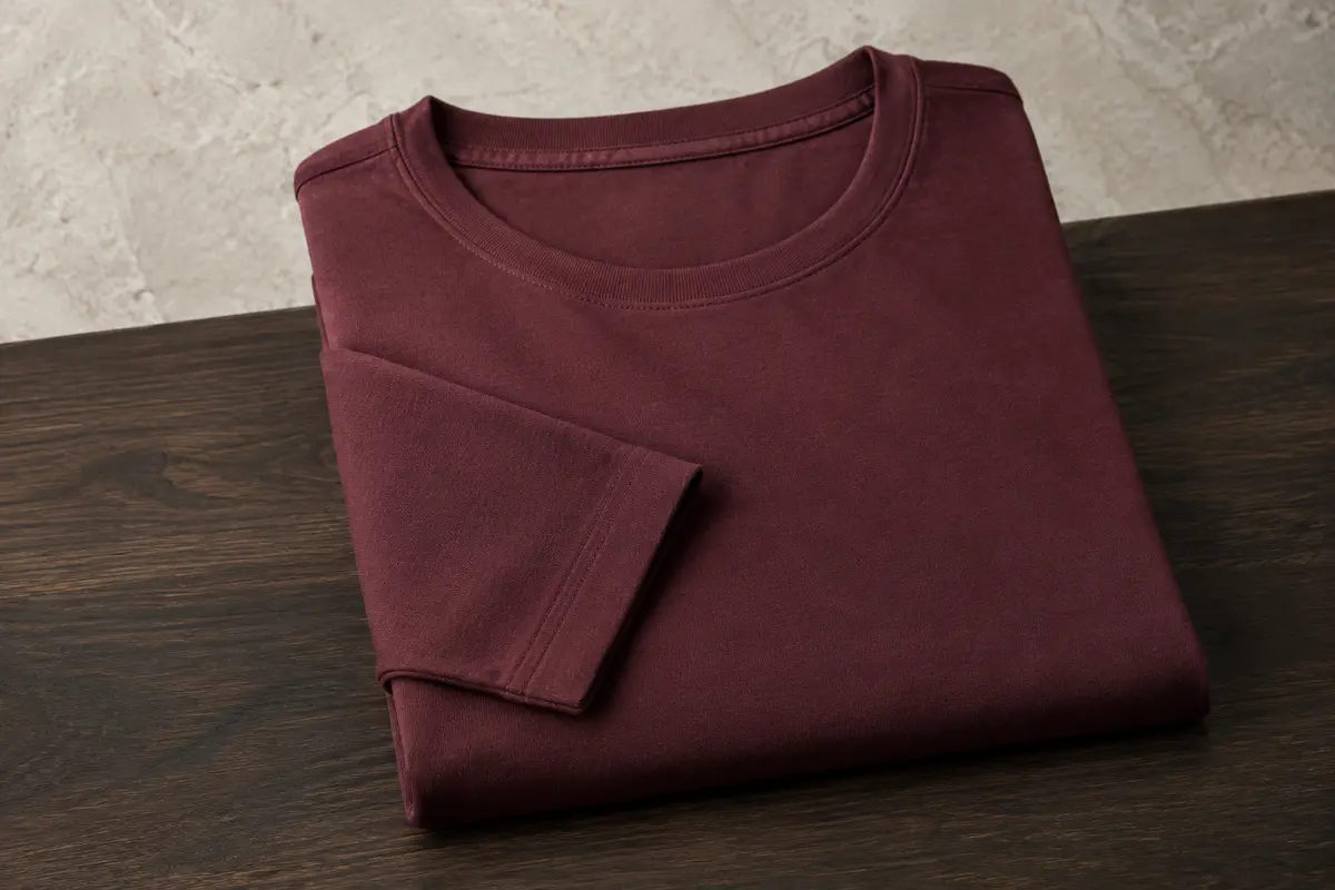 T-shirt homme en coton à manches longues et col rond, plié seul sur une surface en bois.